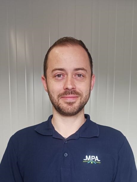 Homme souriant portant un polo bleu, portrait professionnel sur fond clair.